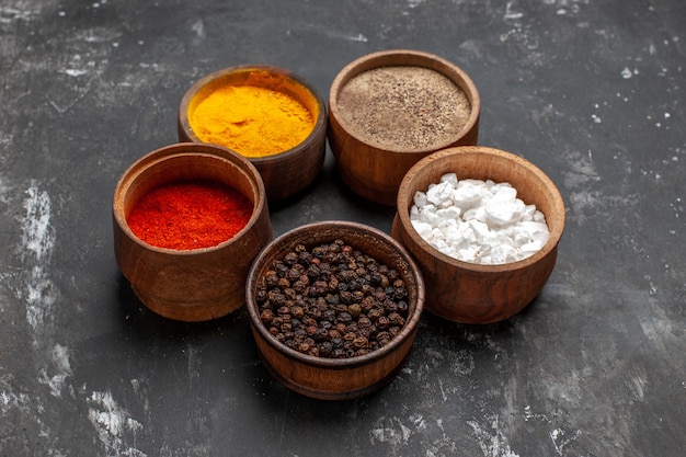 front-view-different-seasonings-inside-little-pots-dark-table-spice-color-pepper_140725-72904